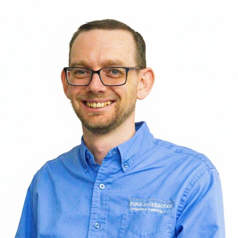Smiling man in glasses wearing a blue button-down shirt against a white background
