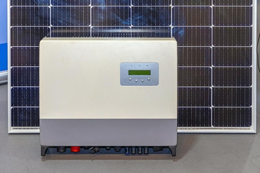 A Solar Panel Inverter is Sitting Next to a Solar Panel — Rob Ward Electrical Services in Kingscliff, NSW