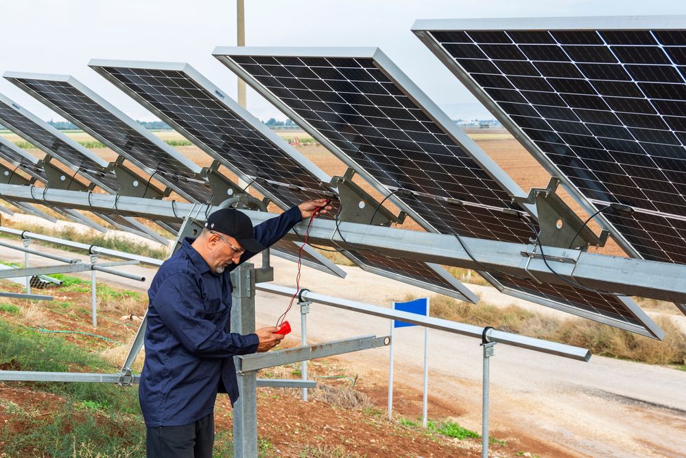 A Man is Working on a Solar Panel in a Field — Rob Ward Electrical Services in Byron Bay, NSW