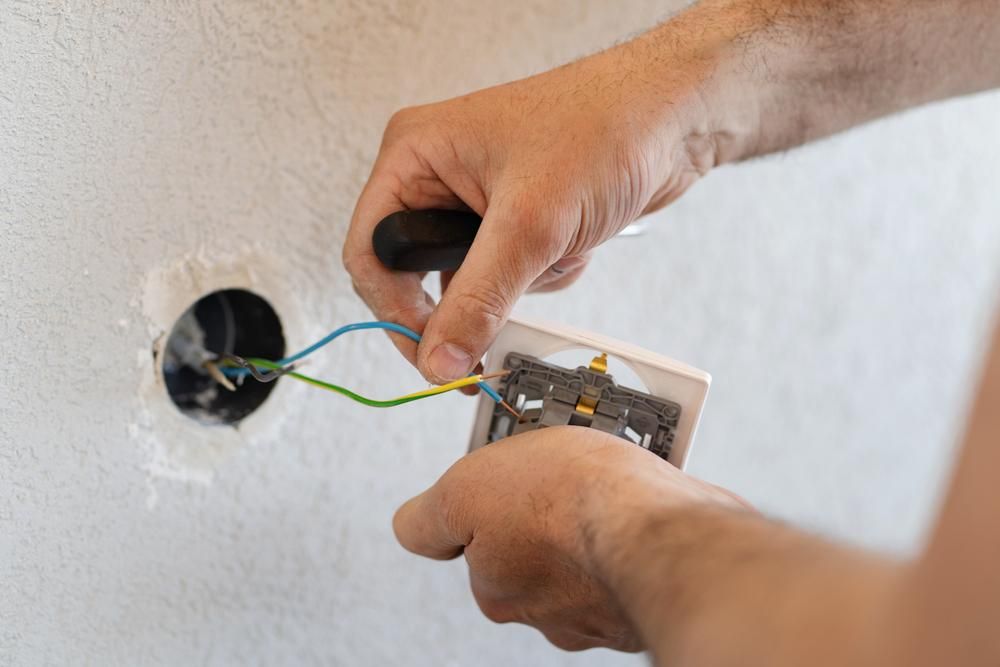 A Person is Installing a Light Switch on a Wall — Rob Ward Electrical Services in Lismore, NSW
