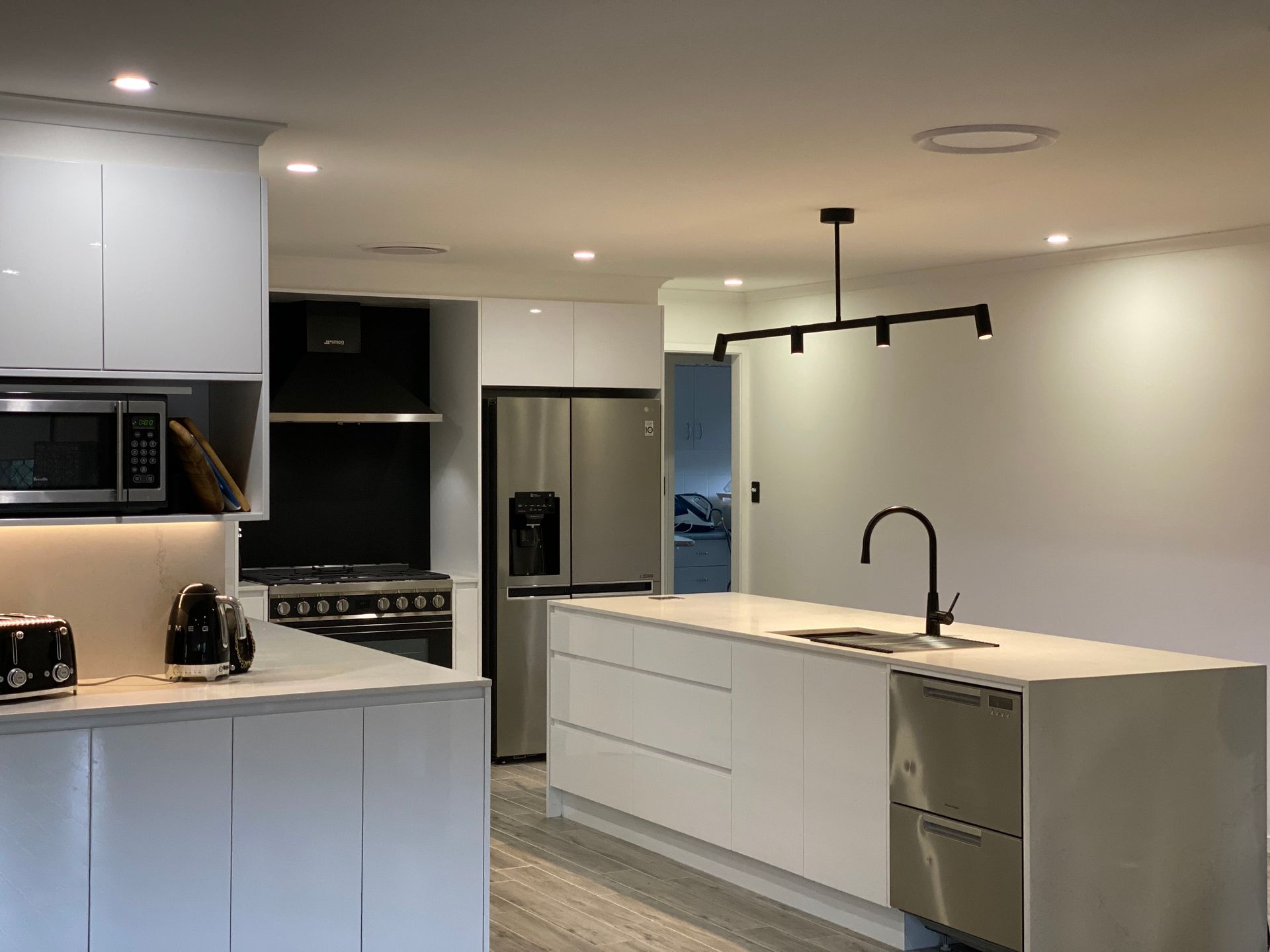 Modern White Kitchen With Stainless Steel Appliances — Rob Ward Electrical Services in Broadwater, NSW