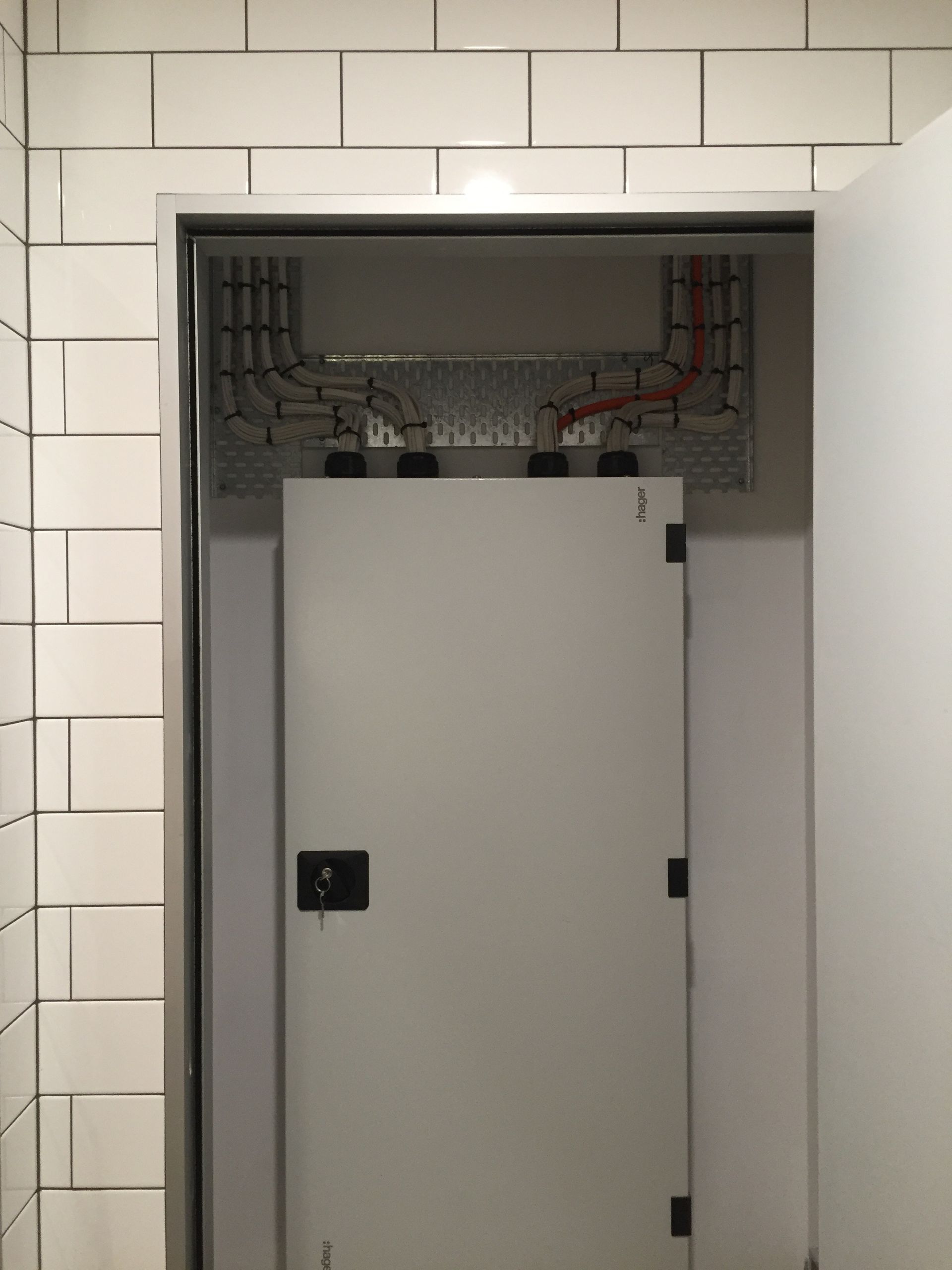 White door inside a tiled doorway, revealing electrical wiring above the door— Rob Ward Electrical Services in West Ballina, NSW