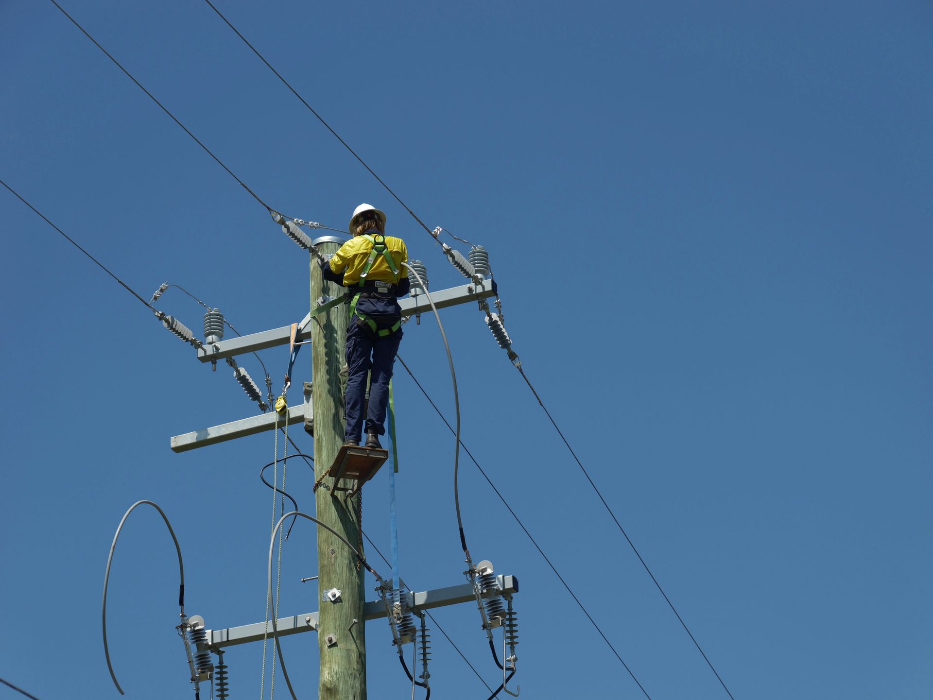 Lineworker on Utility Pole, Wearing Safety Harness — Rob Ward Electrical Services in Byron Bay, NSW