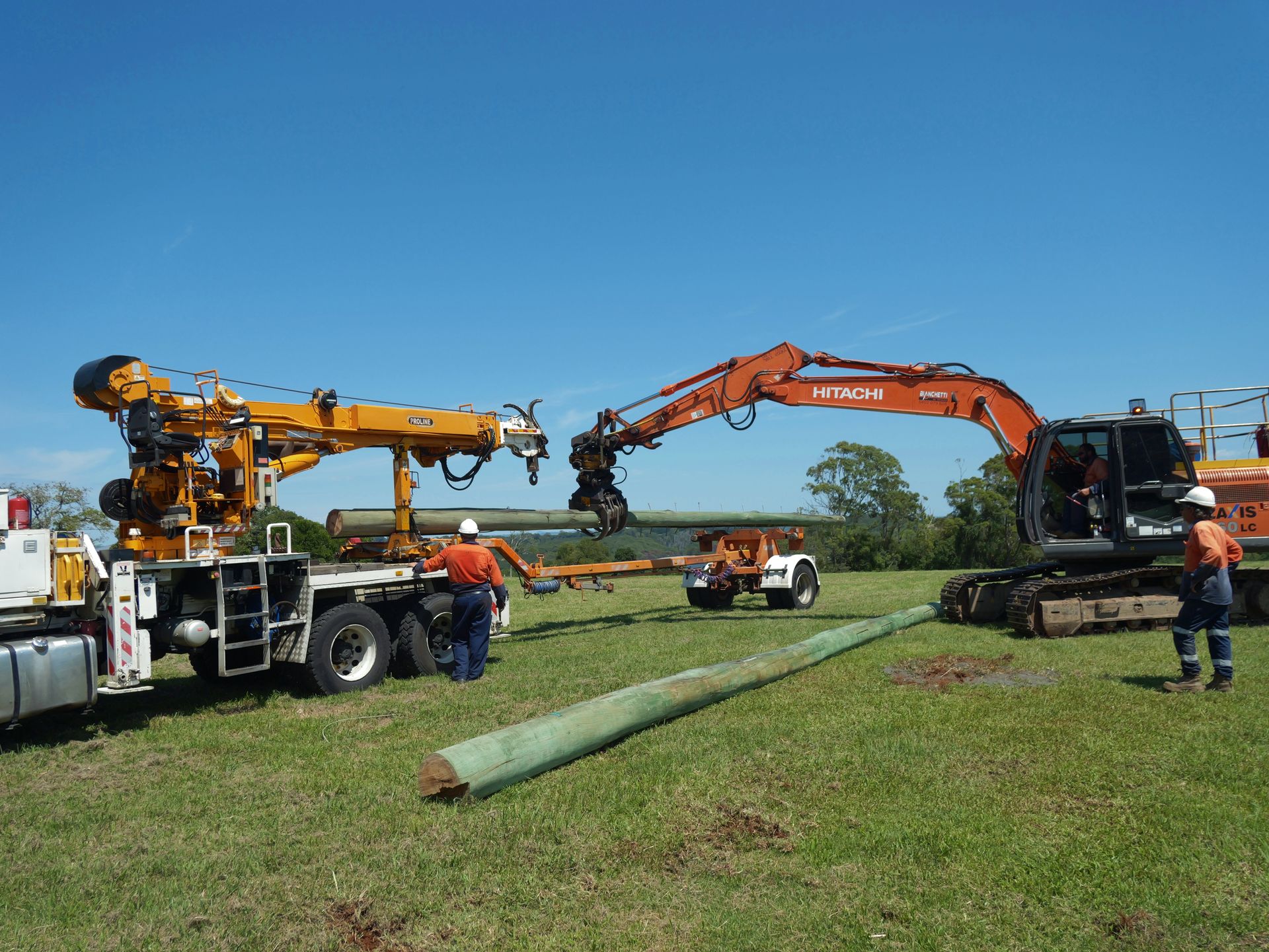 Truck-mounted Drill and Excavator Working Together to Install a Utility Pole in a Field — Rob Ward Electrical Services in Bangalow, NSW