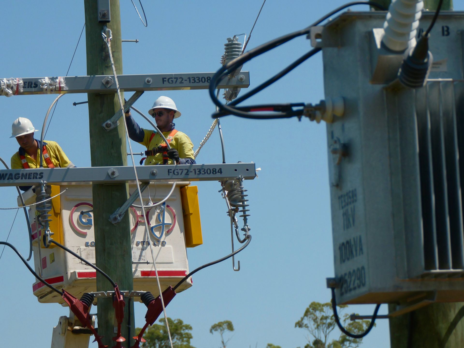 Linemen in bucket truck working on power lines attached to a transformer, blue sky— Rob Ward Electrical Services in West Ballina, NSW