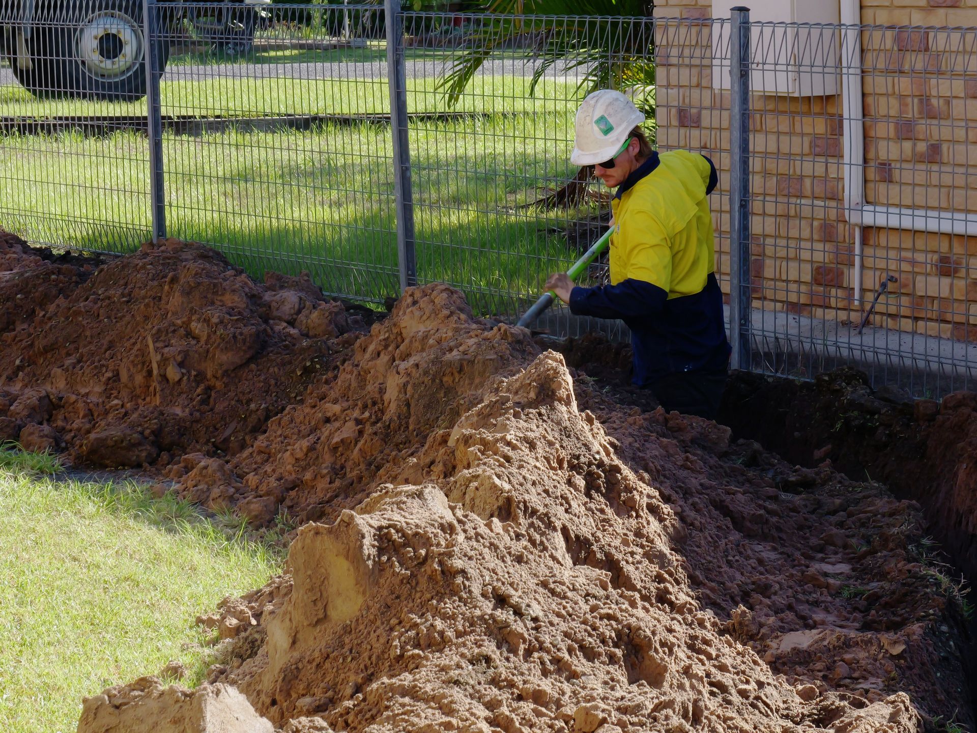Construction Worker Digging a Trench Near a Building — Rob Ward Electrical Services in Byron Bay, NSW