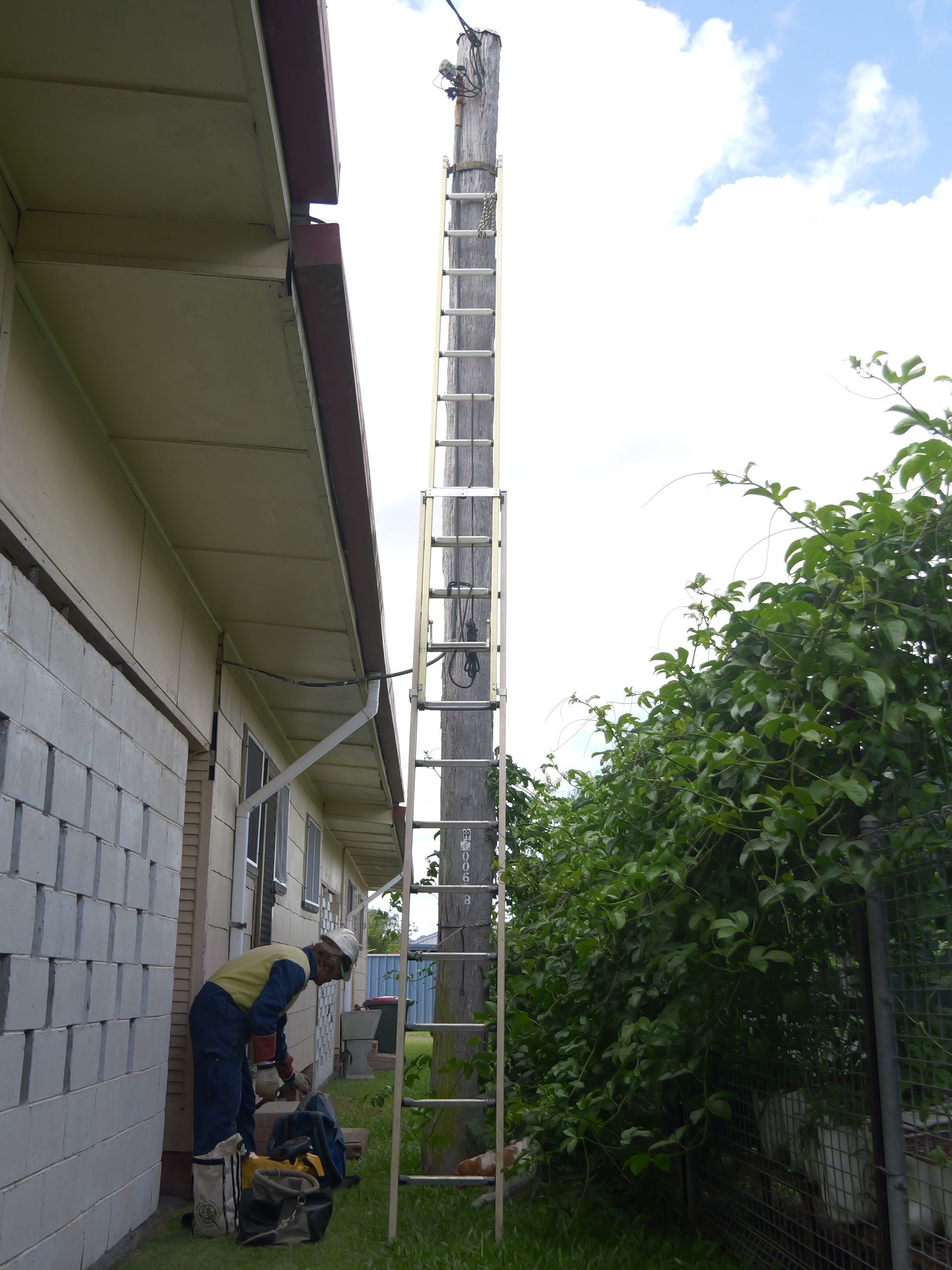 A Person in Work Clothes Near the Base of a Tall Utility Pole — Rob Ward Electrical Services in Wardell, NSW