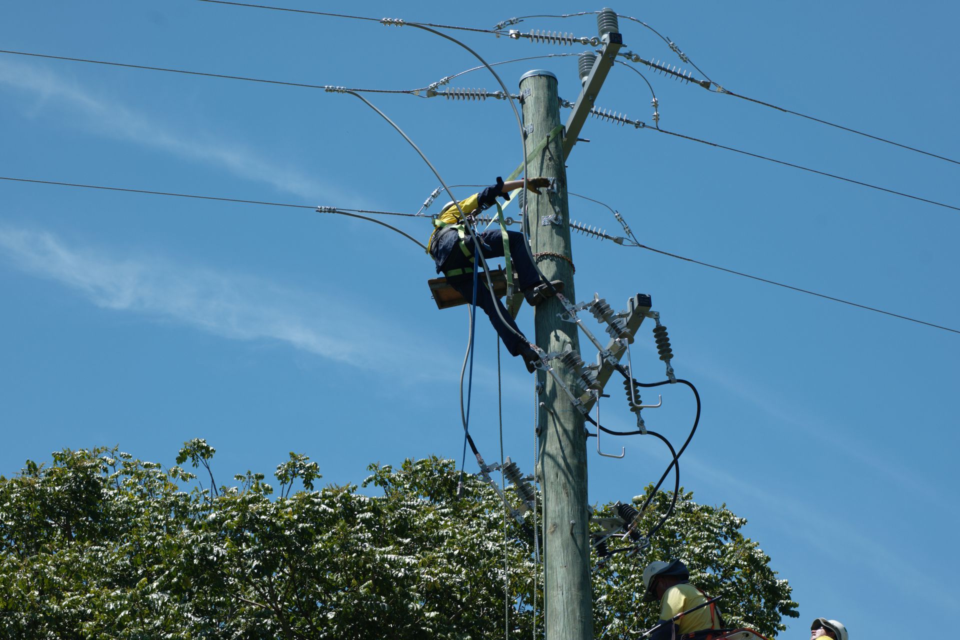 Lineman Working on Power Lines Atop a Wooden Utility Pole — Rob Ward Electrical Services in Lismore, NSW