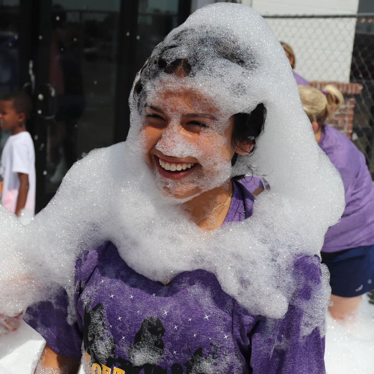 A woman in a purple shirt is covered in foam