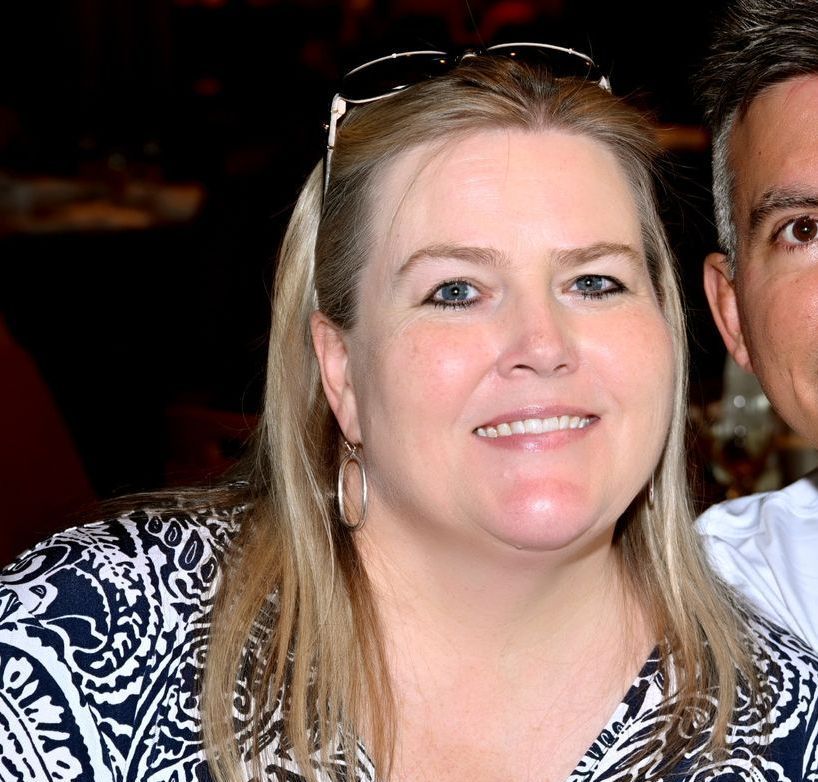 A man and a woman are posing for a picture and the woman is wearing sunglasses.