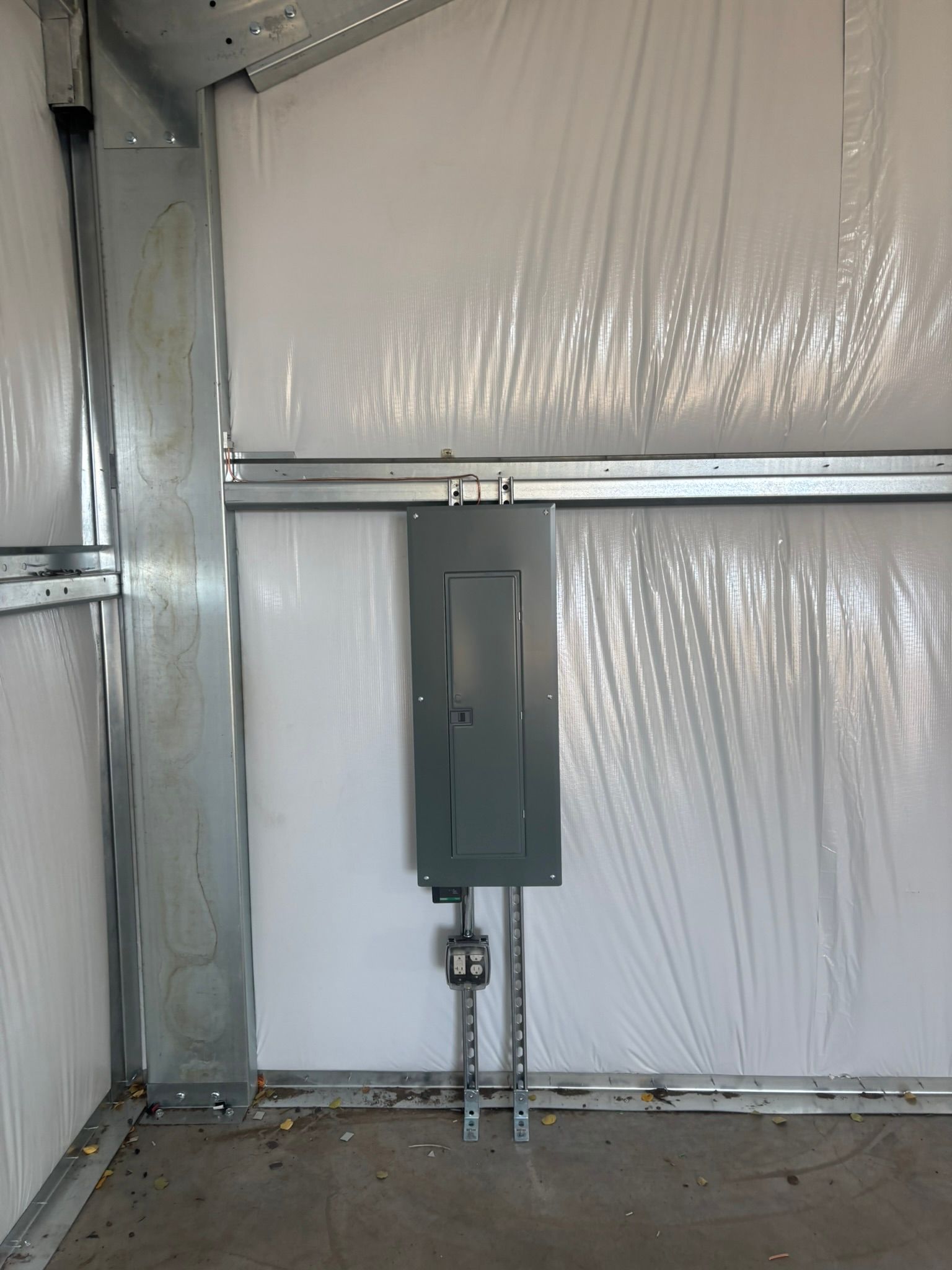 Electrical panel mounted on a wall in a metal-framed structure.