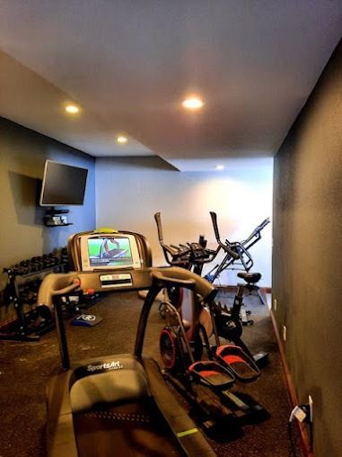 Home gym with treadmill, elliptical, stationary bike, and TV.