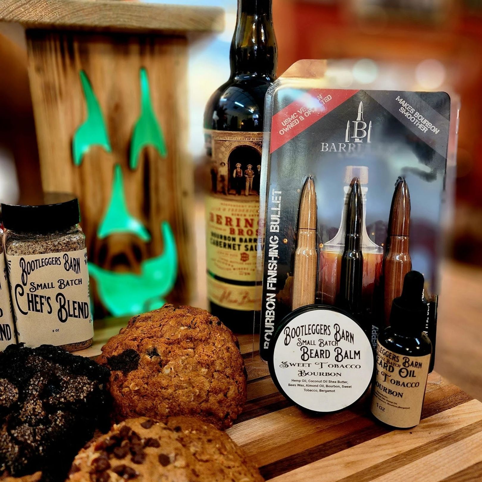Halloween-themed display with glowing green jack-o'-lantern, cookies, and assorted spooky candles on a wooden table