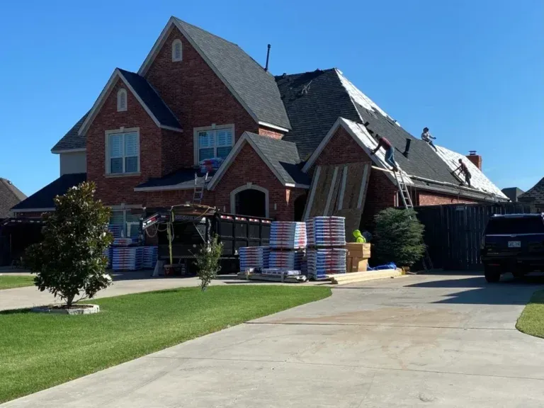 Suburban brick house under construction with stacked materials, driveway, and black truck outside