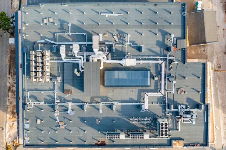 Aerial view of a flat industrial rooftop with HVAC units, vents, and ductwork.