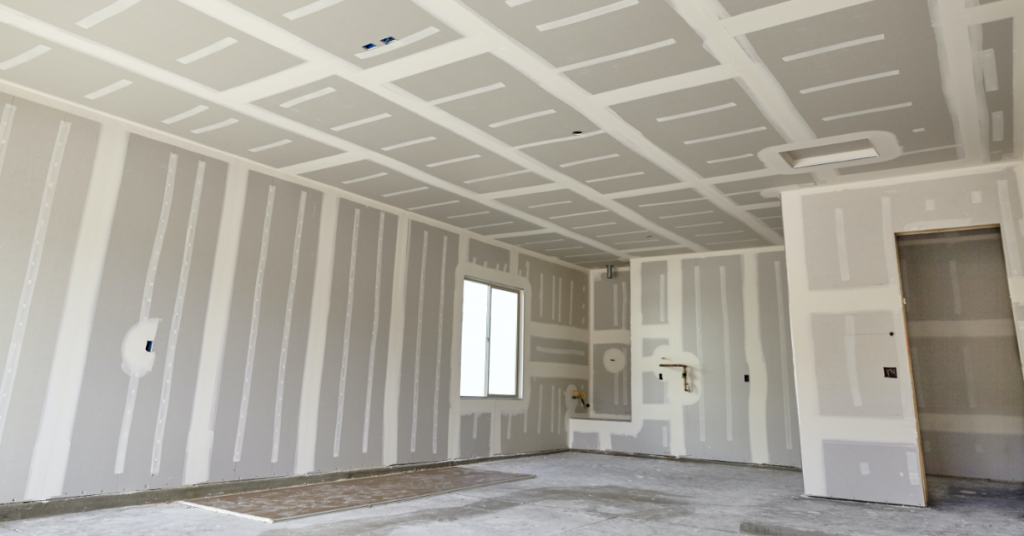 Empty drywall room with taped seams, windows, a doorway, and a concrete floor under construction