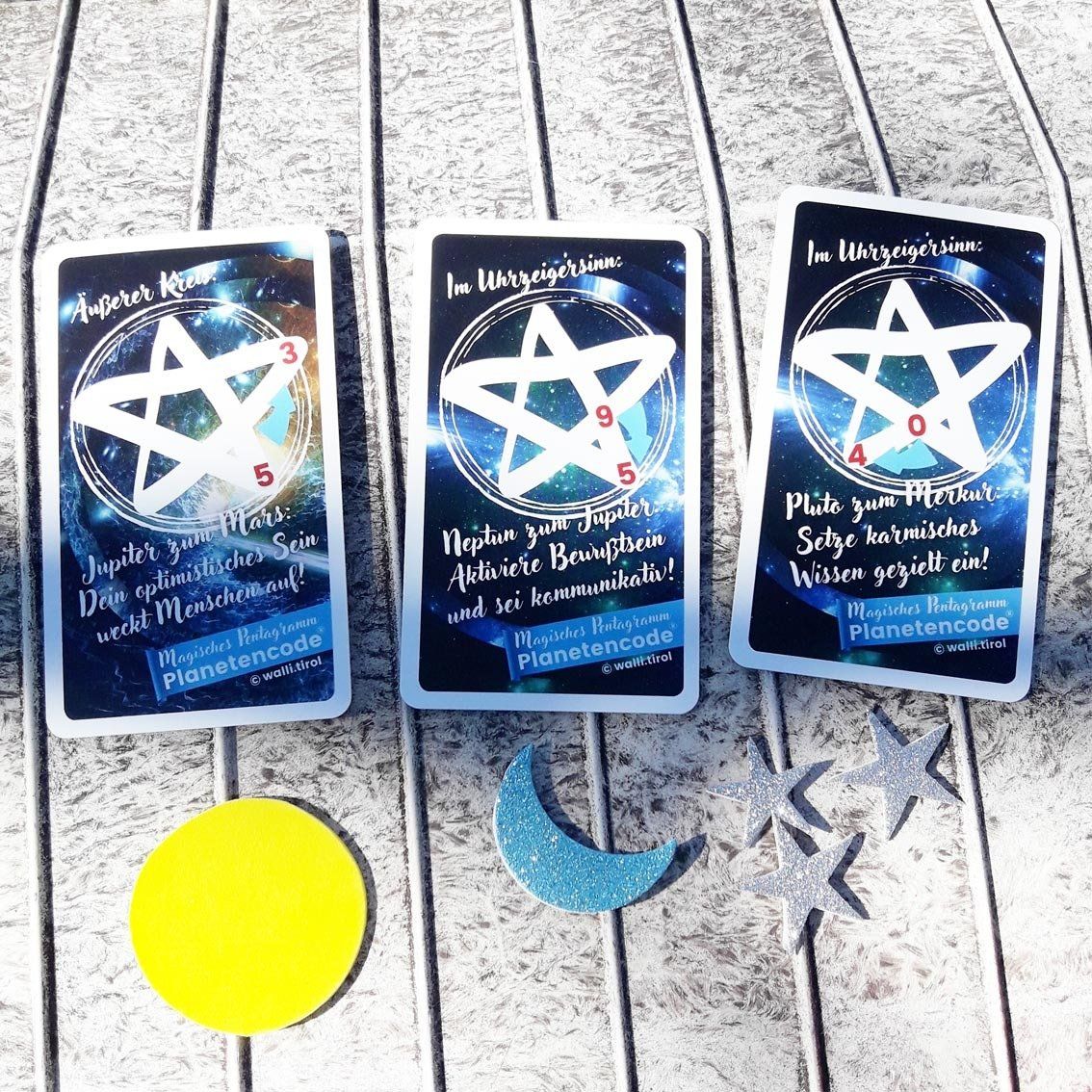 Drei Tarotkarten mit Pentagrammen auf grauem Holzgrund, darunter Ausschnitte von gelbem Mond und blauer Mondsichel.