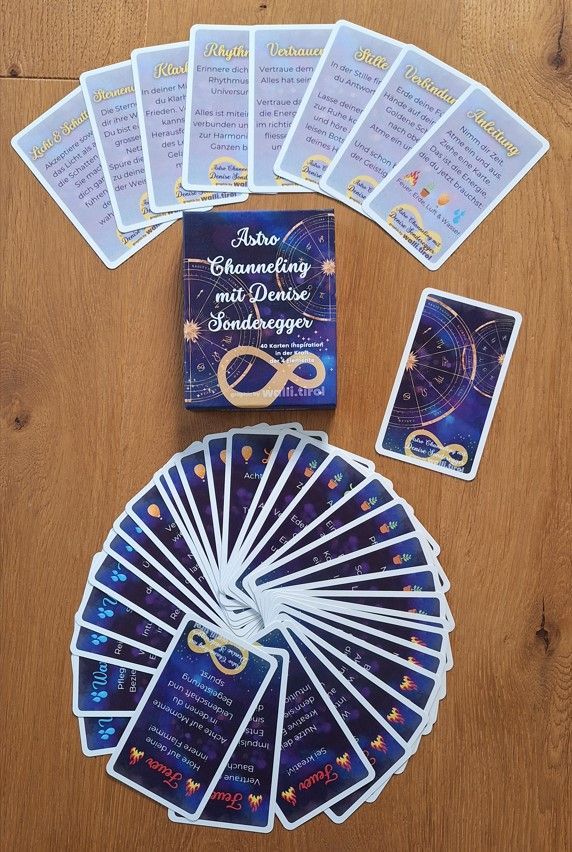 Ein blaues Tarot-Deck liegt auf einem Holztisch ausgebreitet, darunter befinden sich ein passendes Begleitheft und ein kreisförmiger Fächer mit Karten.