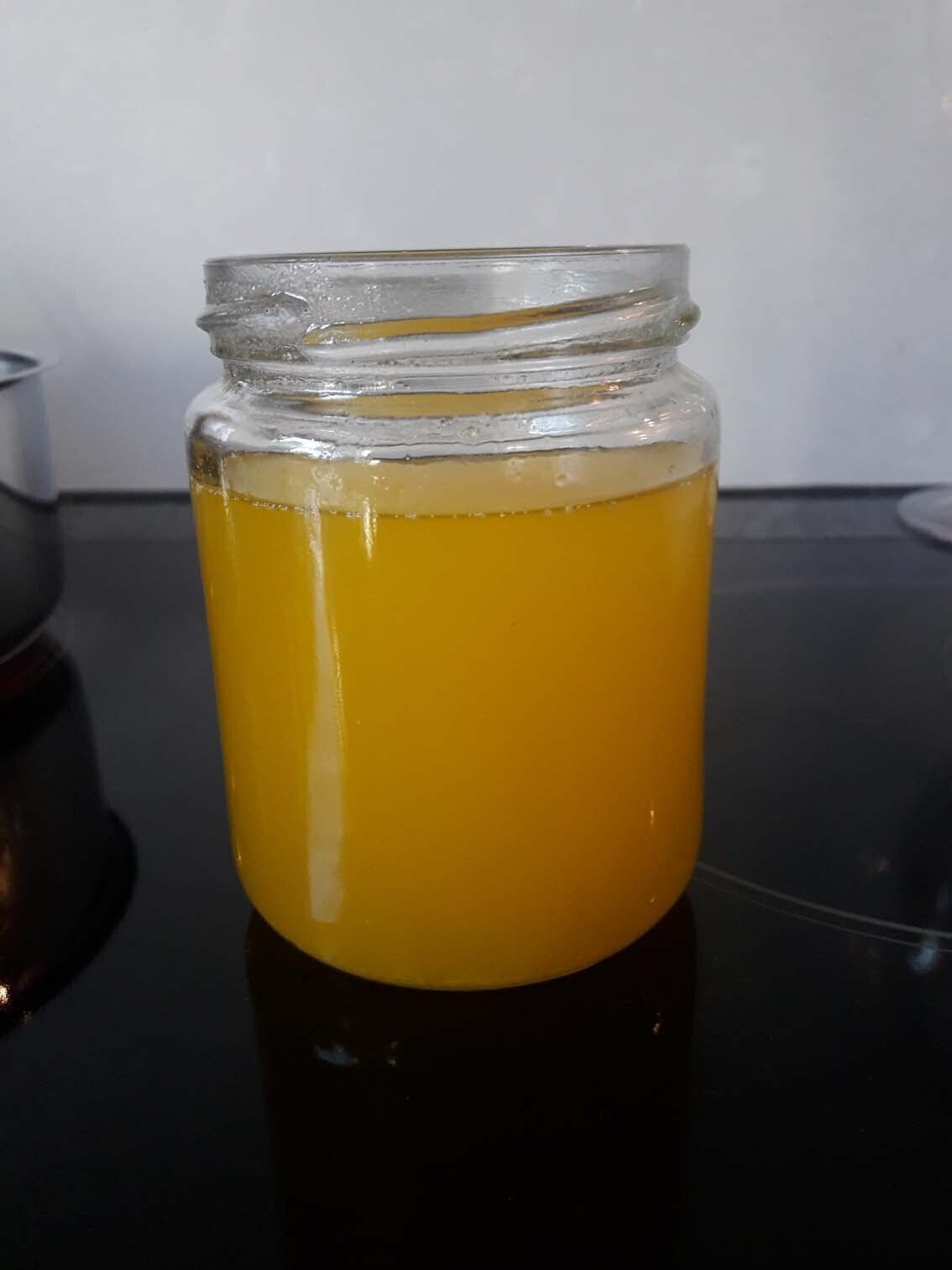 Ein Glasgefäß gefüllt mit trüber gelber Flüssigkeit auf einer dunklen Arbeitsfläche