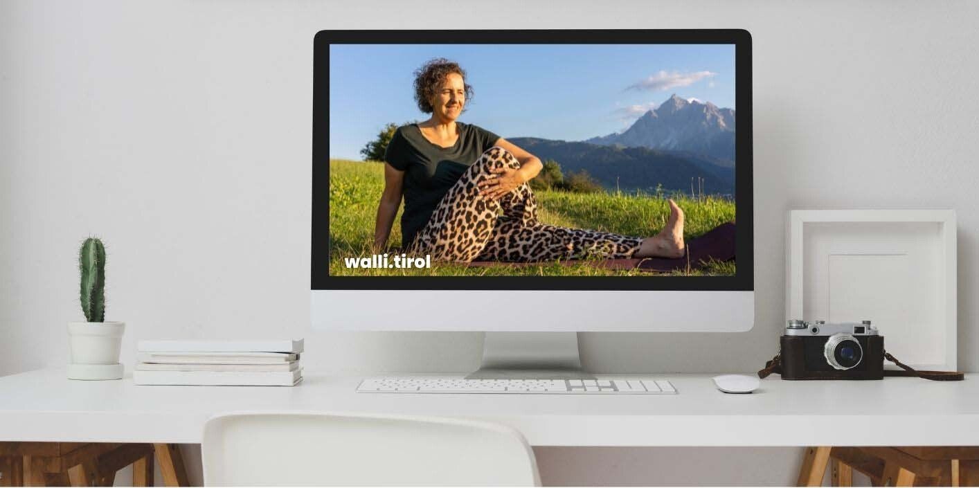 Minimalistischer weißer Schreibtisch mit einem großen Monitor, der eine Landschaftsaufnahme zeigt, und einer Kamera auf der rechten Seite.