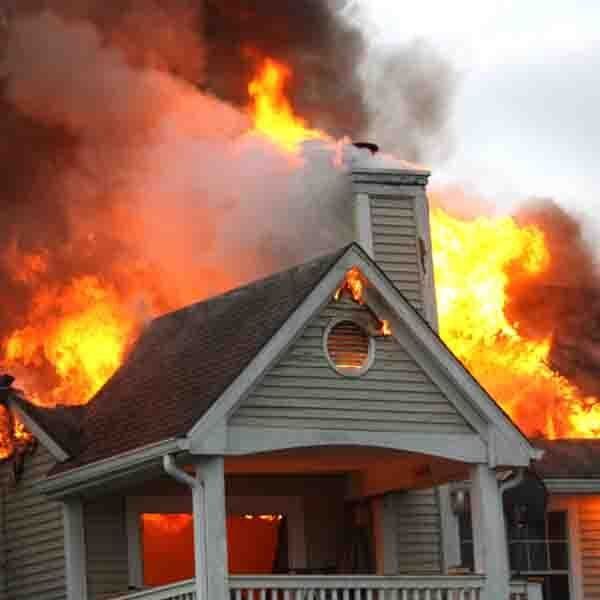 House engulfed in flames; fire visible through windows and roof.