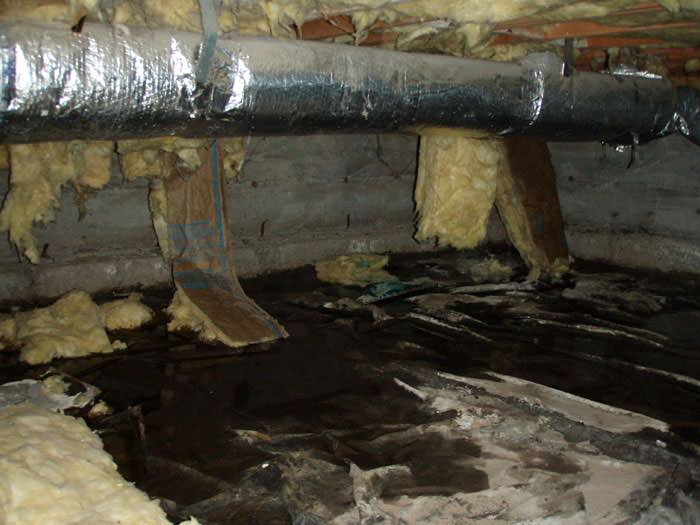 Dark crawl space with water, insulation, and ductwork.