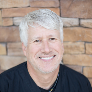Best general dentist in Lee's Summit, MO and surrounding areas. A man with gray hair is smiling in front of a brick wall.
