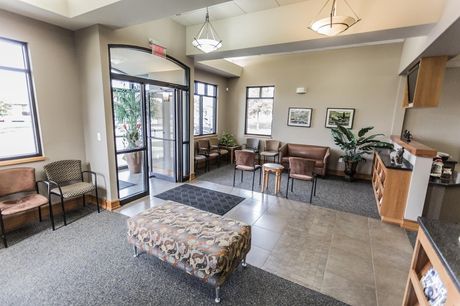 Best family dentist in Lee's Summit, MO and surrounding areas. A waiting room with a bench , chairs , tables and a door.