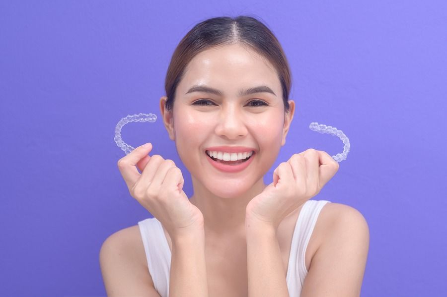 woman smiling holding clear aligners | invisalign treatments near Lees Summit MO
