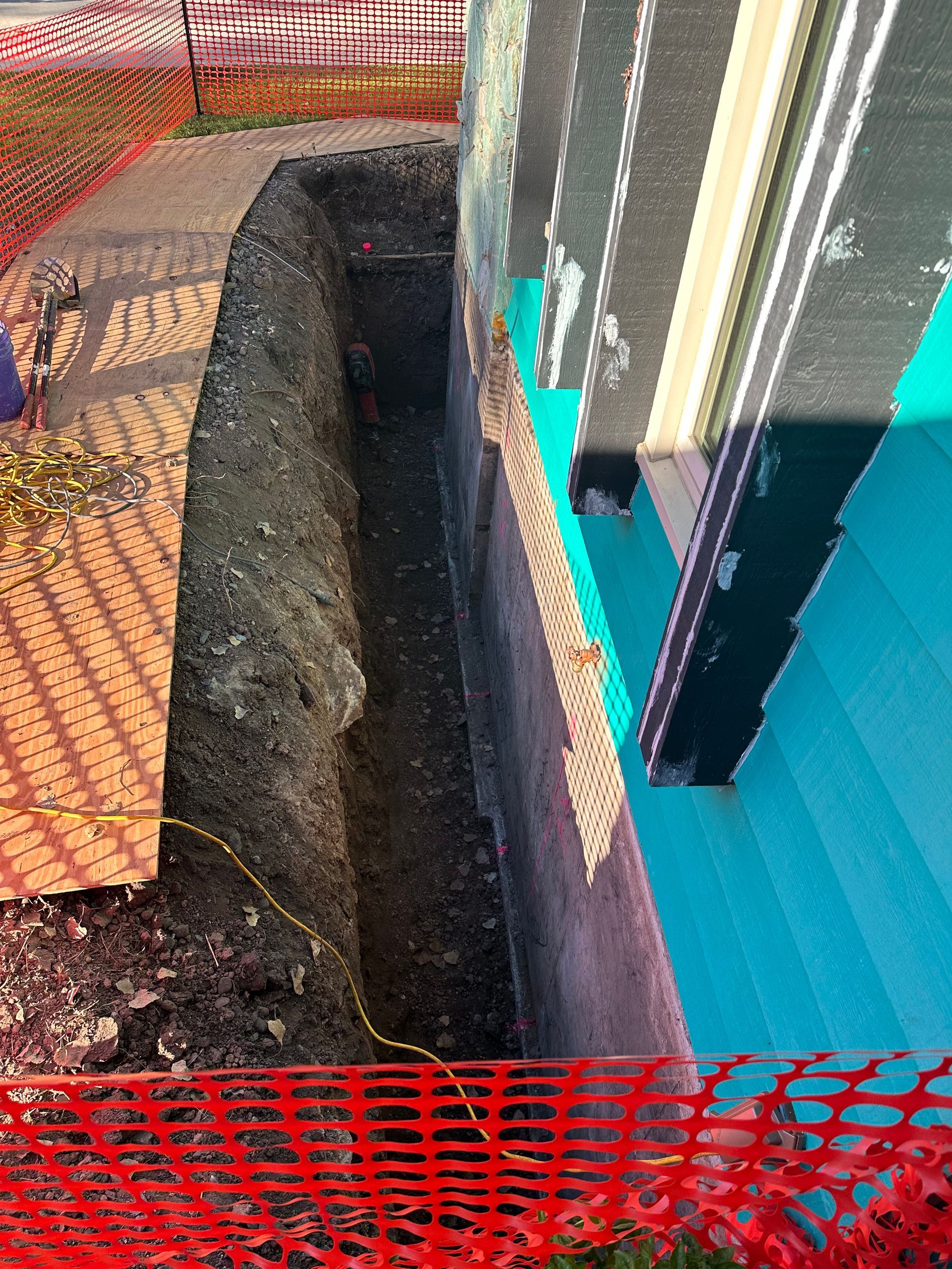 A man is digging a hole in the ground in front of a building.