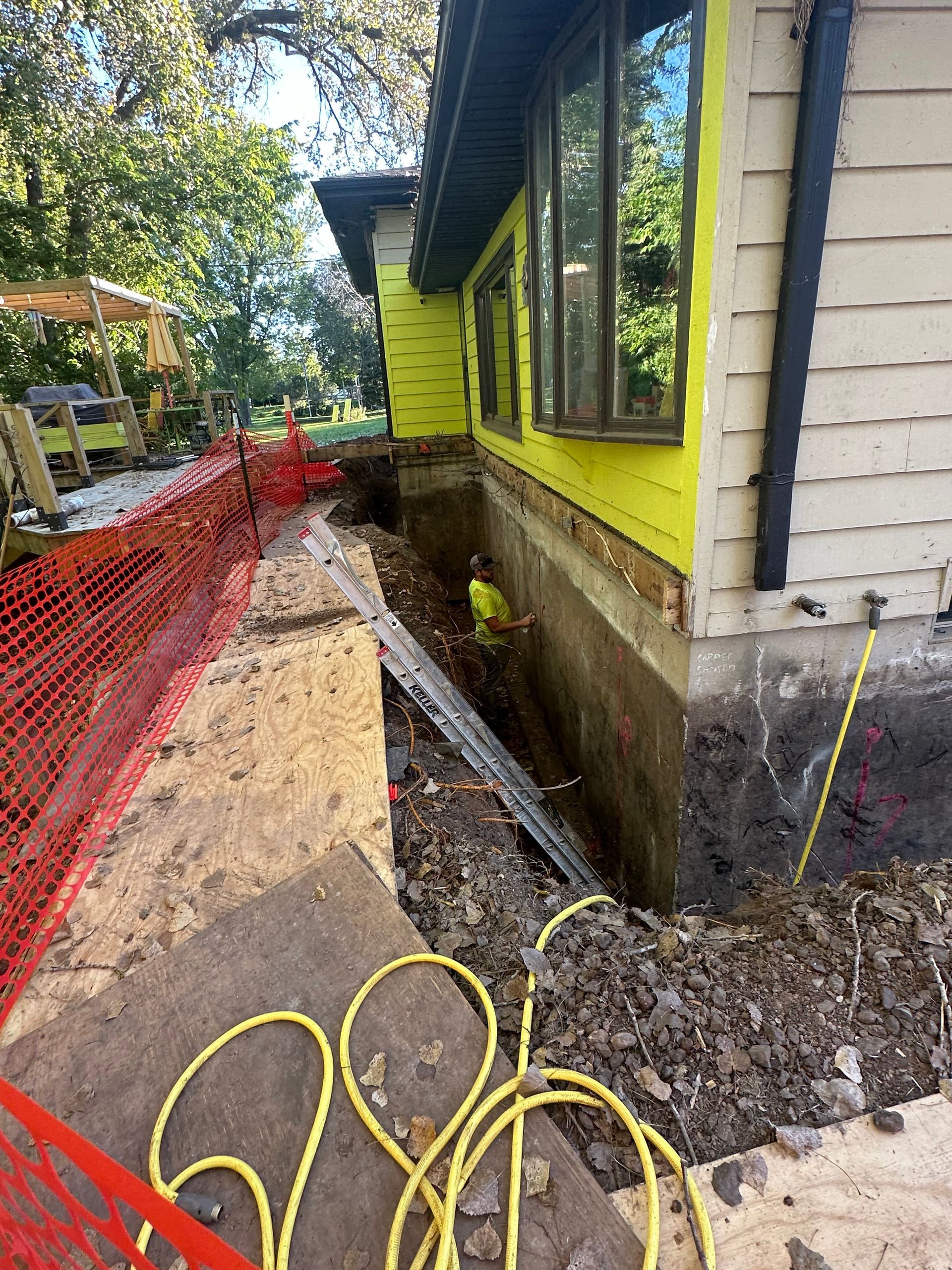 A house is being remodeled and a hose is laying on the ground in front of it.