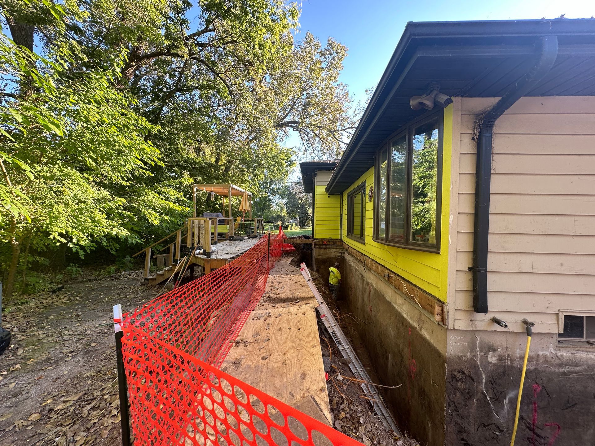 A yellow house is being built next to an orange fence.