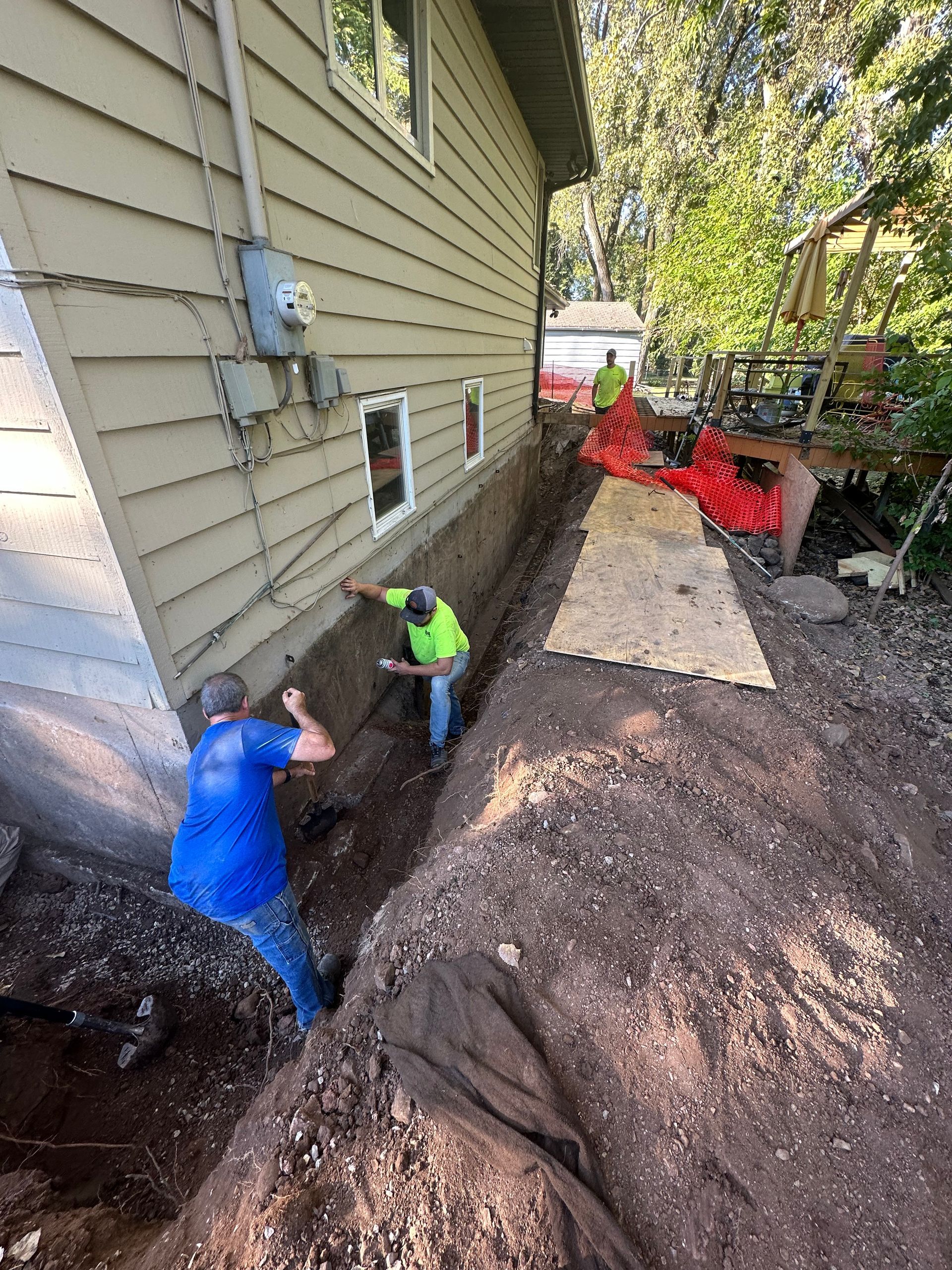 A couple of men are digging a hole in front of a house.