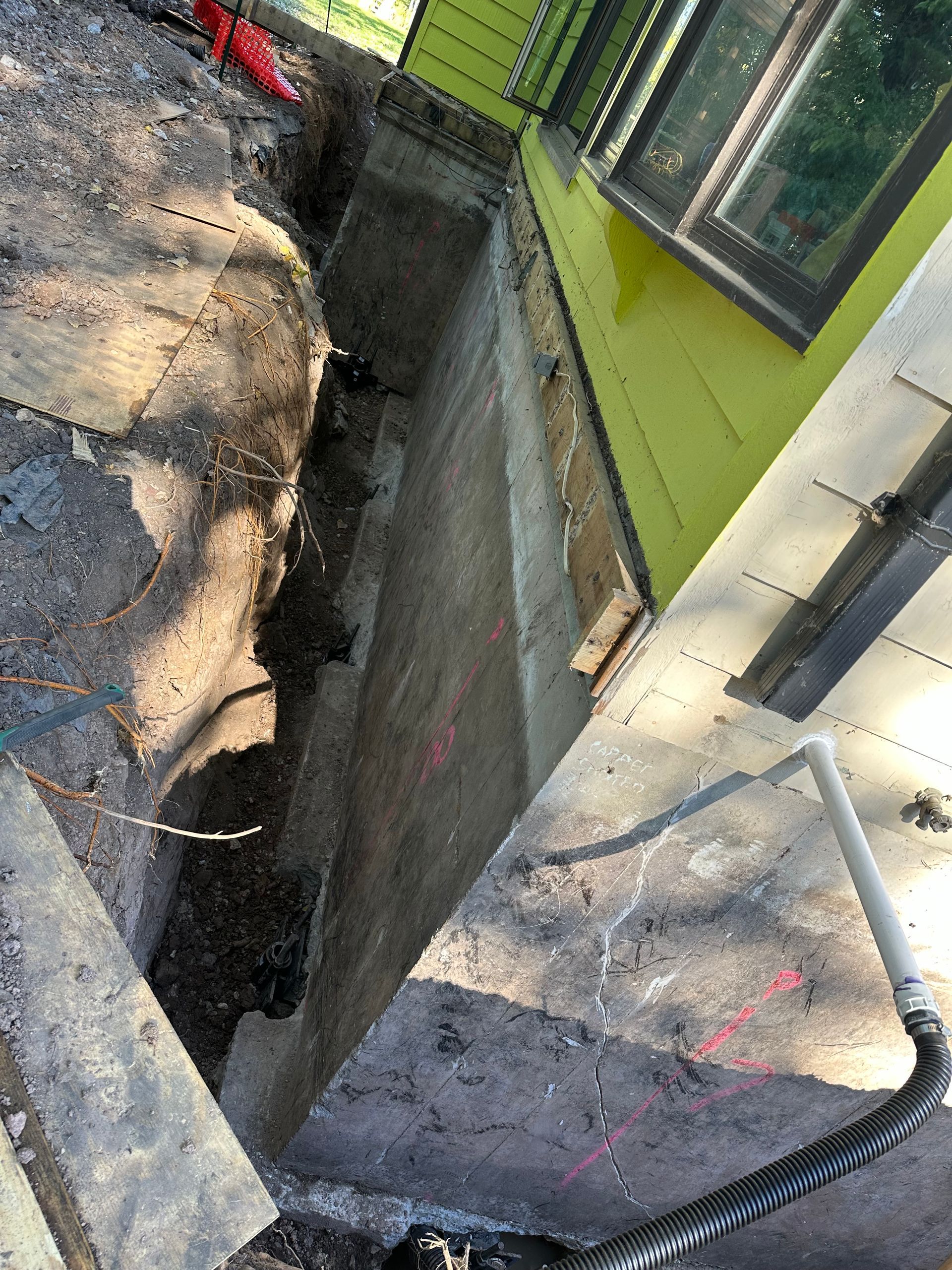 A concrete wall is being built next to a green house.