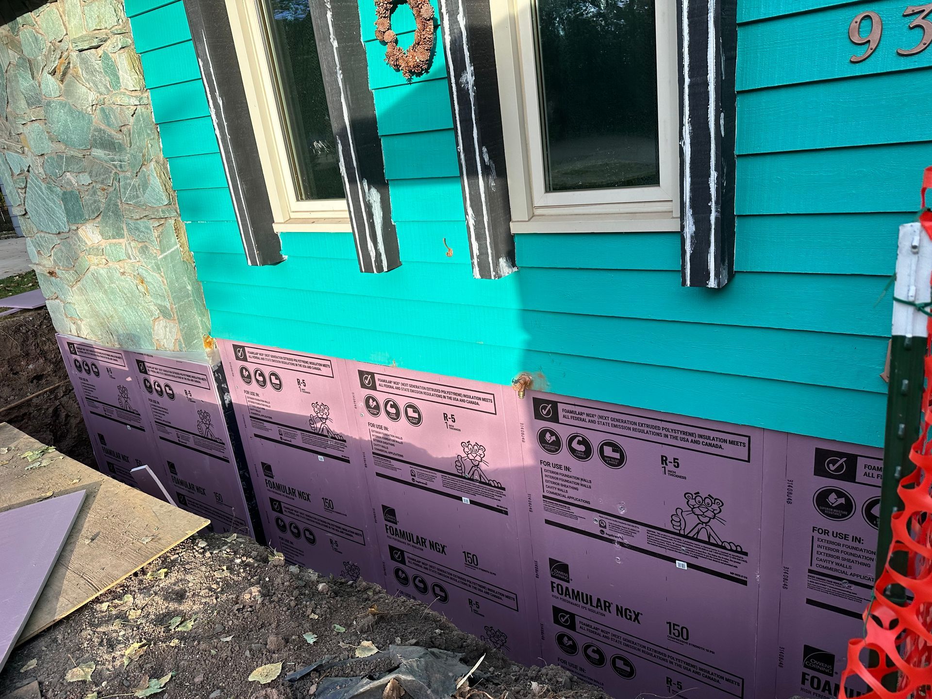 A blue house with purple insulation on the side of it.