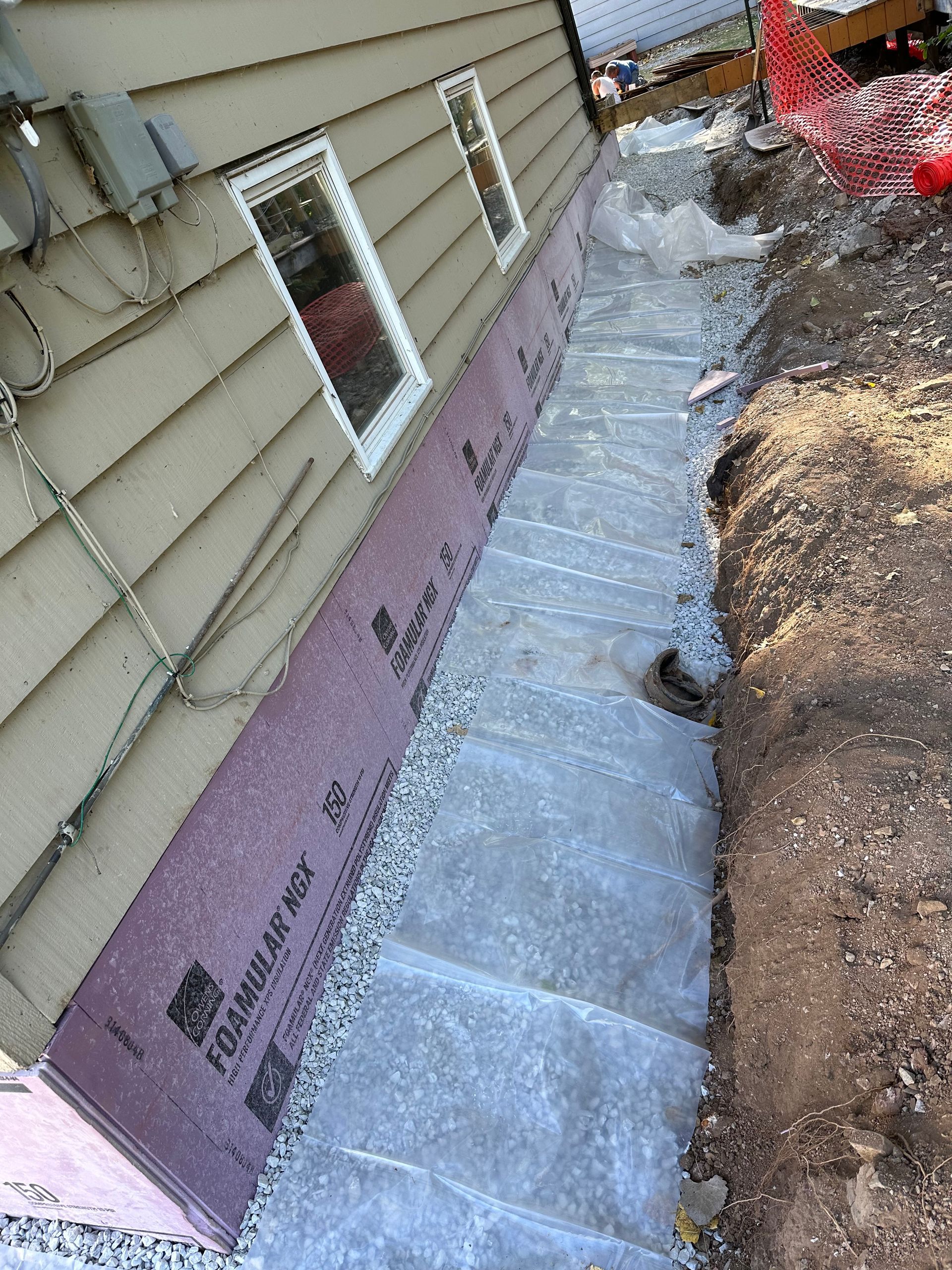 A house with a drainage system being installed on the side of it.