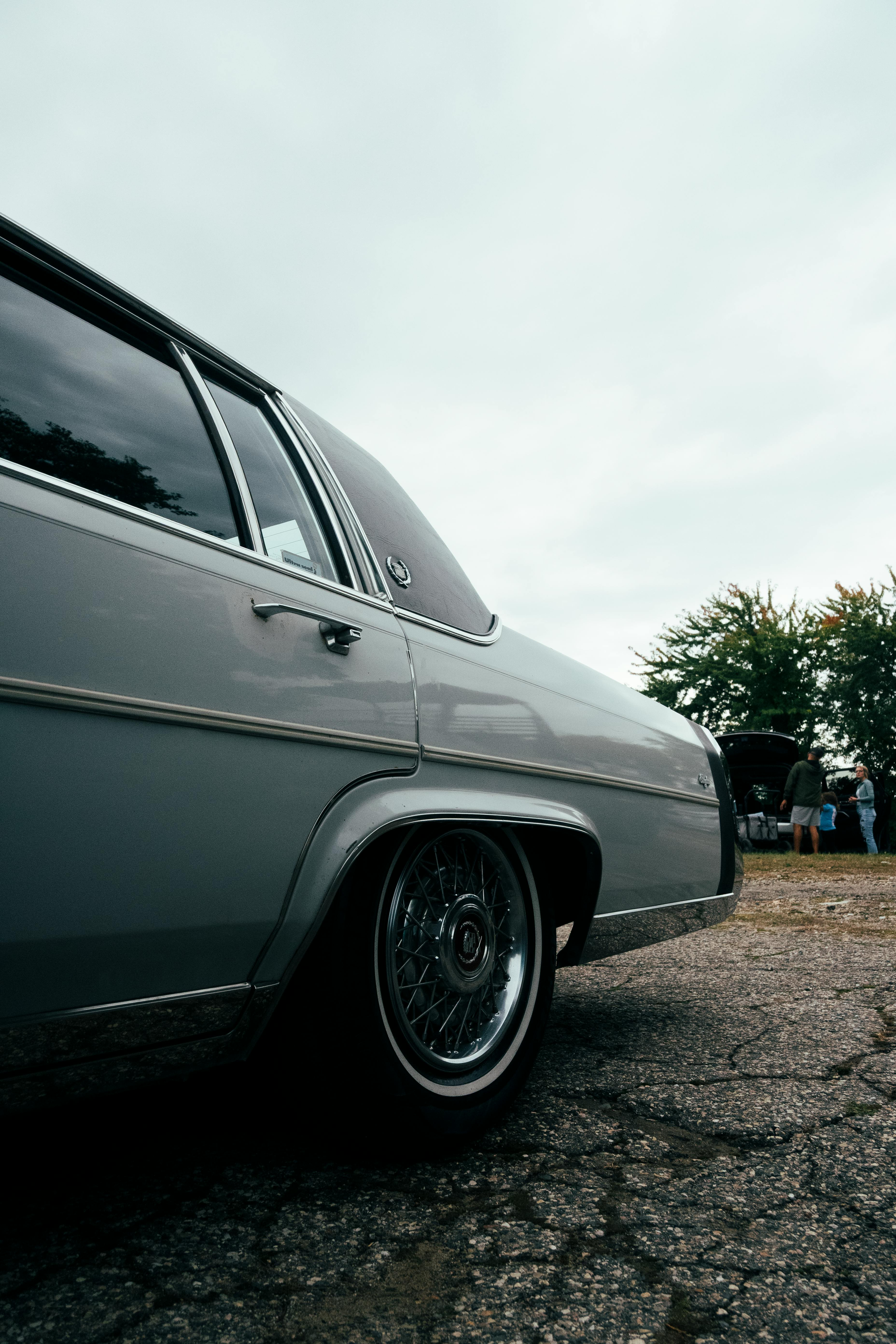 Classic gray car parked on gravel under an overcast sky