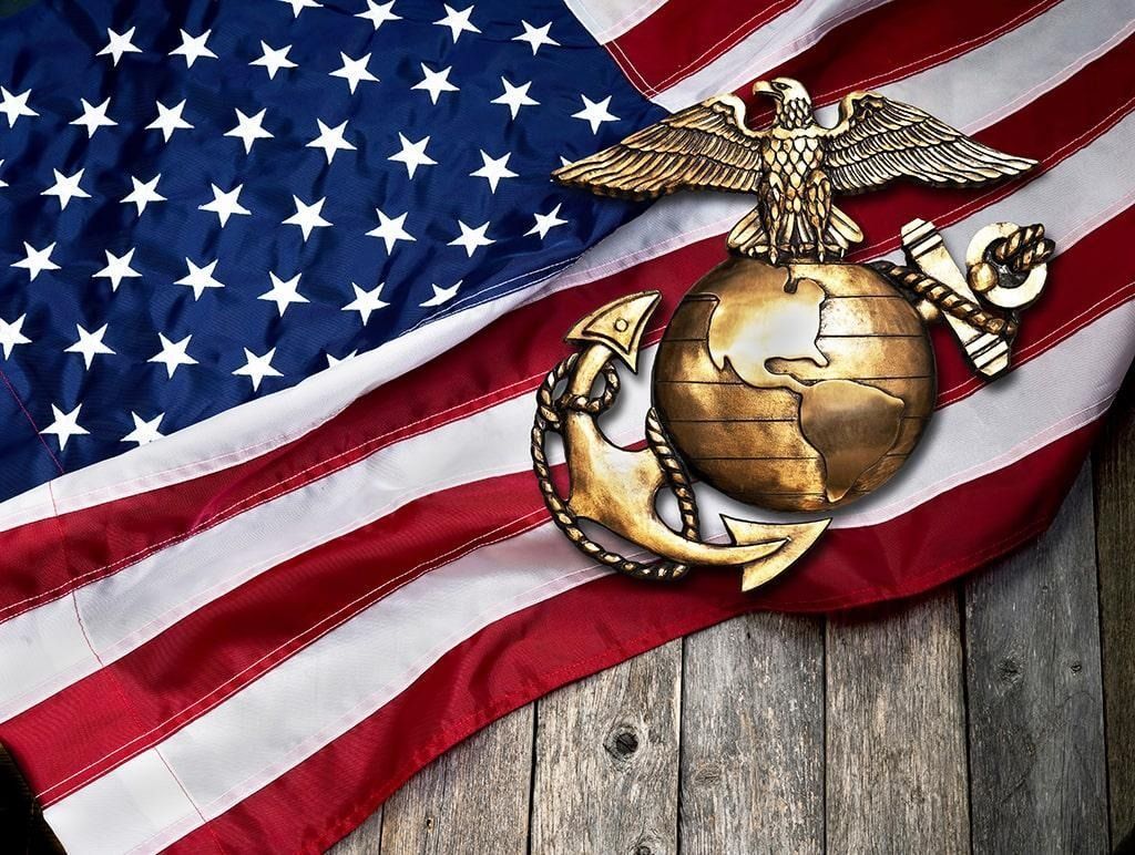 U.S. Marine Corps emblem over an American flag on a weathered wooden background