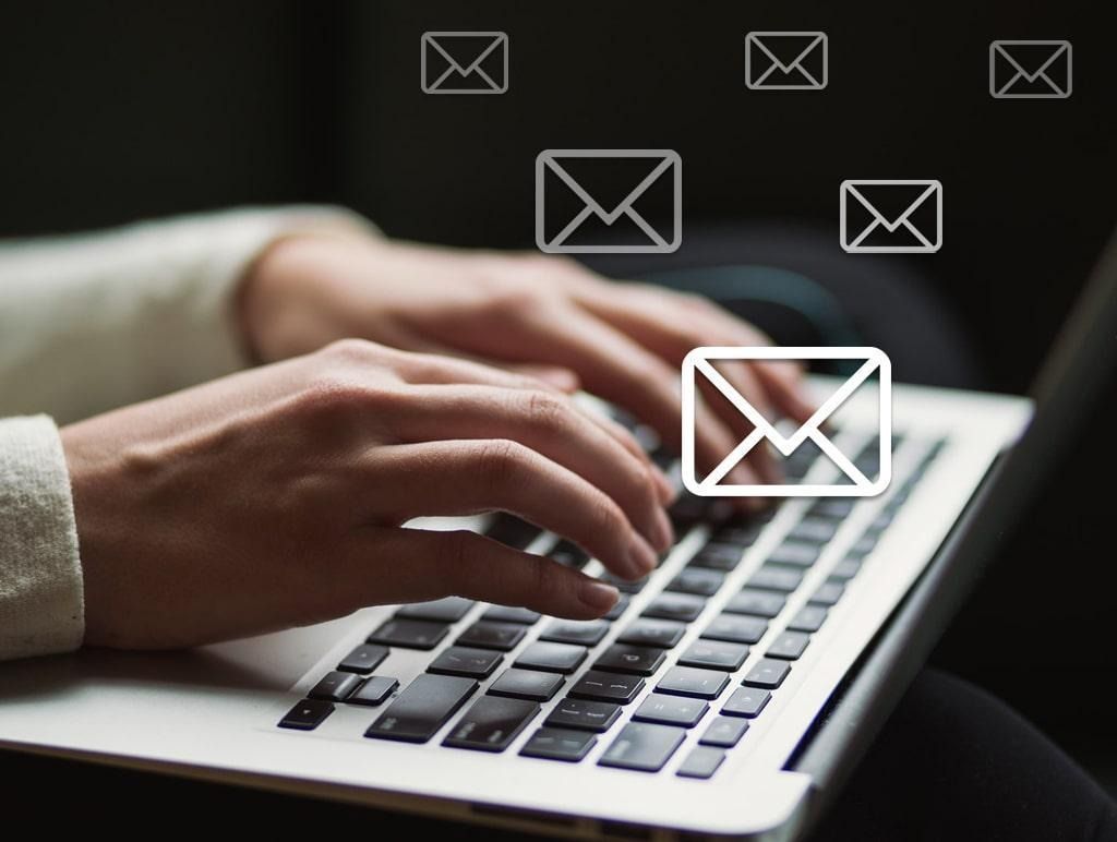 Hands typing on a laptop with floating email icons on a dark background
