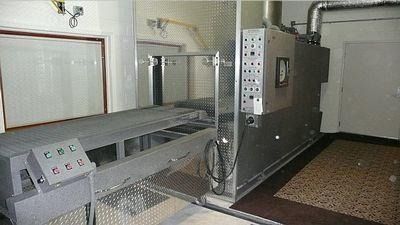 Industrial machine with long metal conveyor in a tiled room