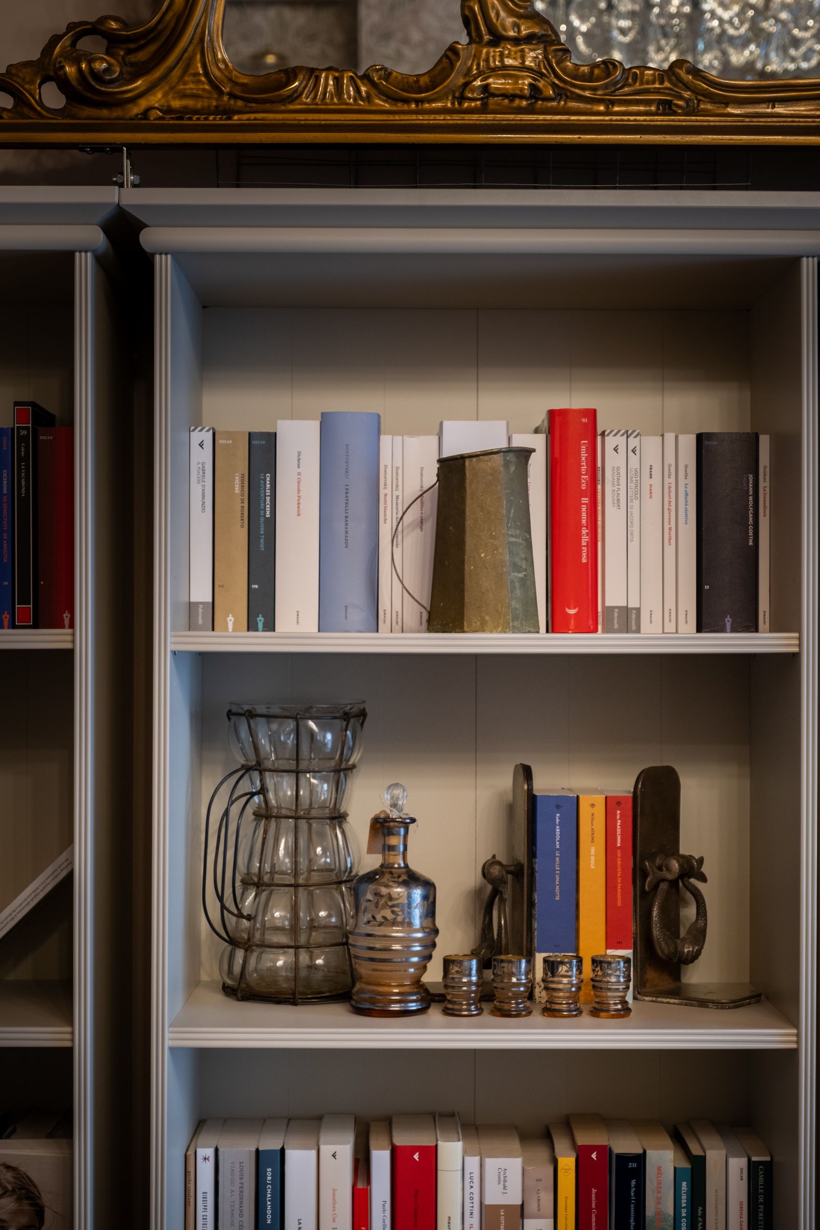 Libri e oggetti decorativi in vetro sugli scaffali di una vetrina.