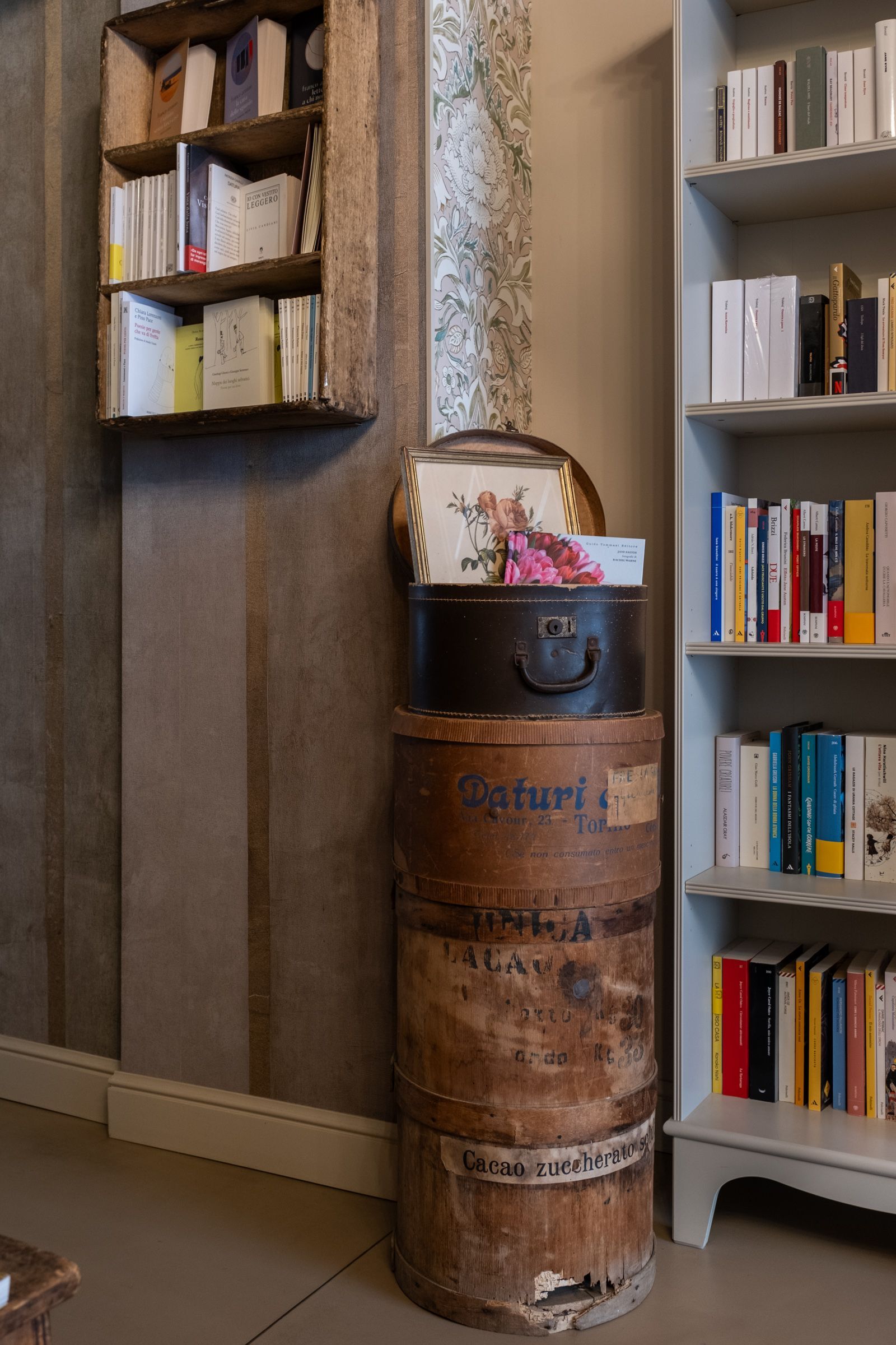 Fioriera rustica a forma di botte con fiori tra due librerie in una stanza simile a una biblioteca.