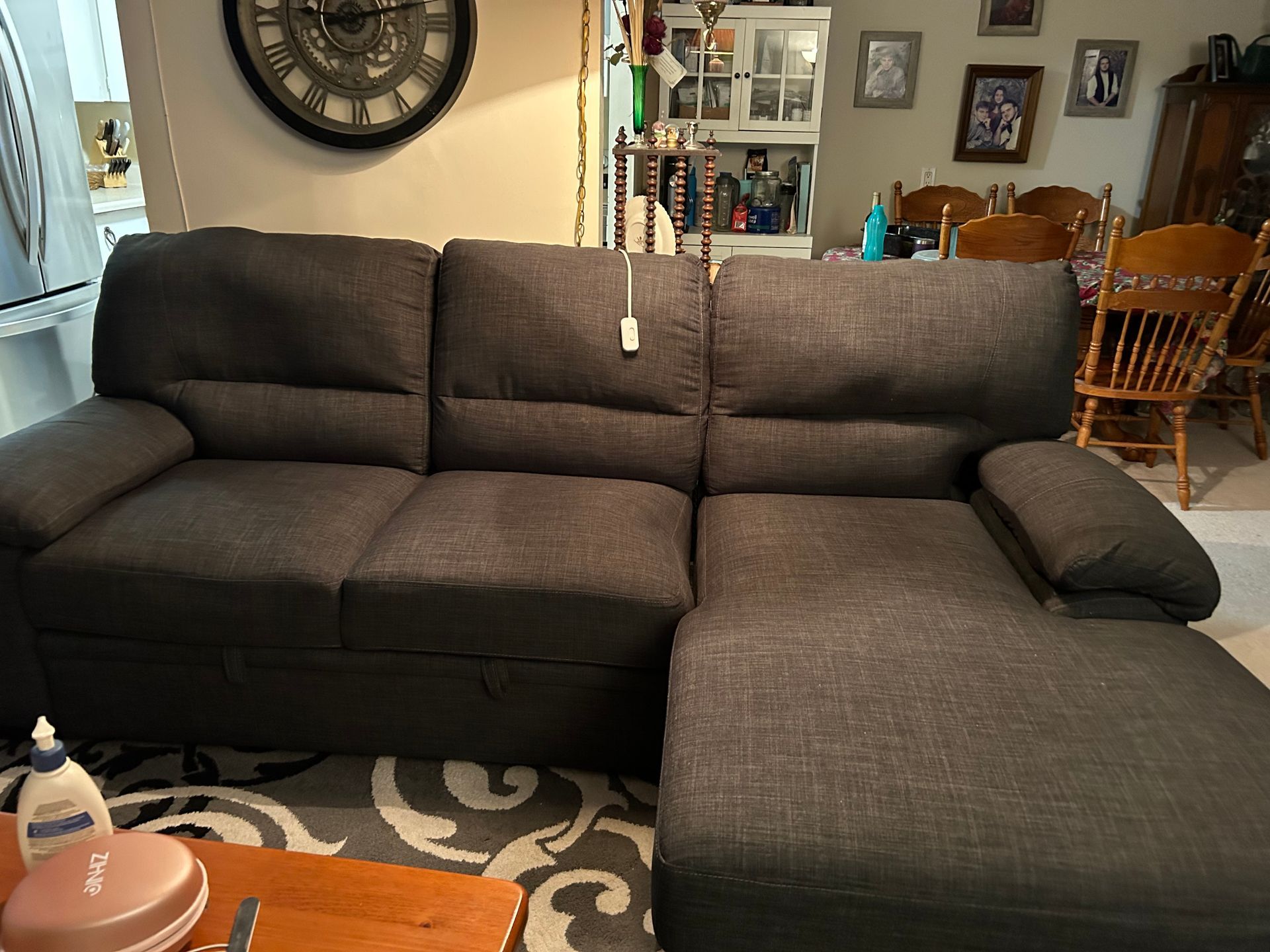 Dark gray sectional sofa in a living room with a patterned rug and wall decor