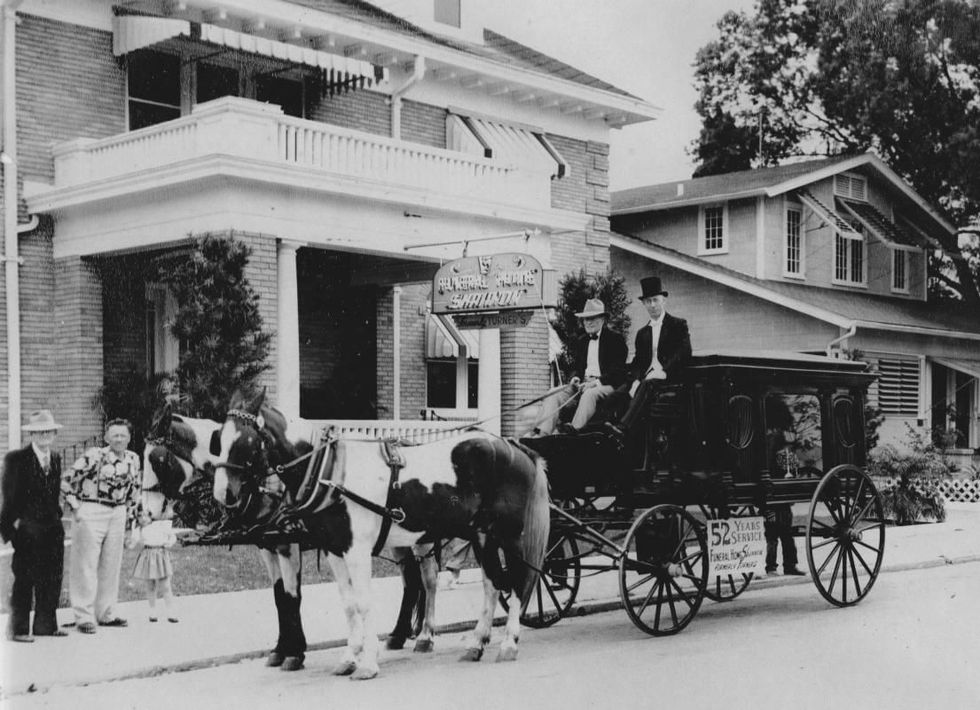 Vintage horse-drawn hearse outside a funeral home, evoking timeless care and tradition.