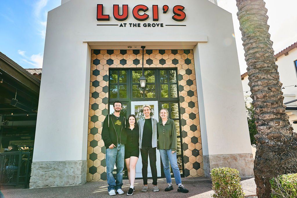 A group of people standing in front of luci 's at the grove 