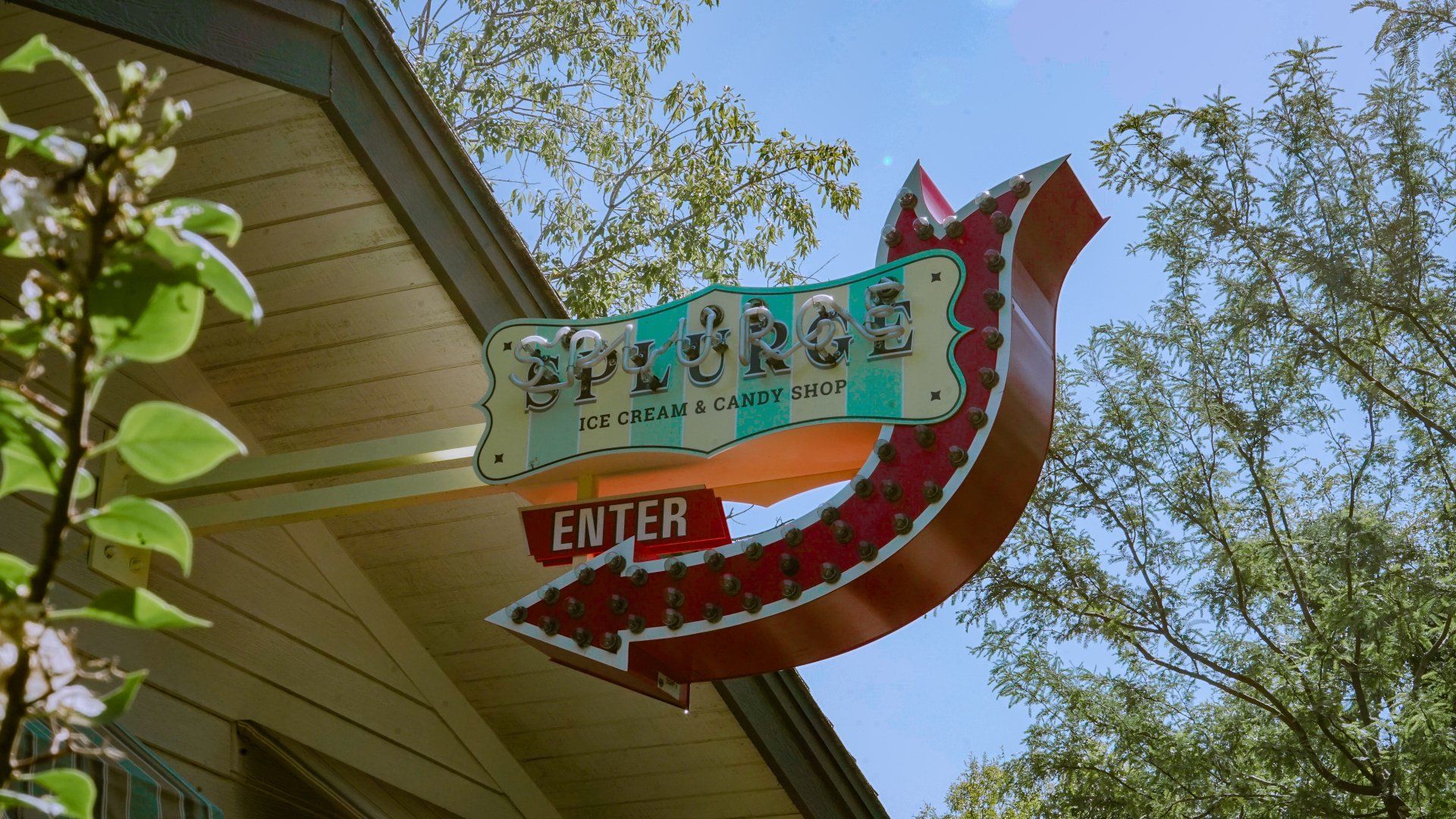 A neon sign on the side of splurge ice cream & candy shop 