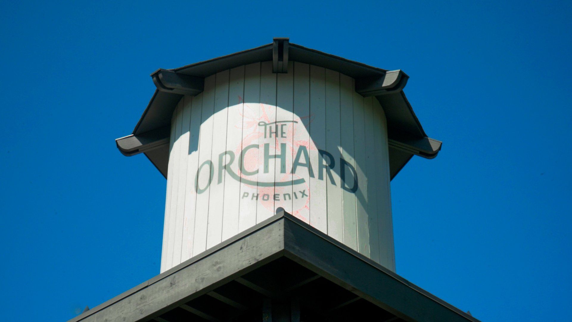 A water tower with the words `` the orchard '' painted on it.