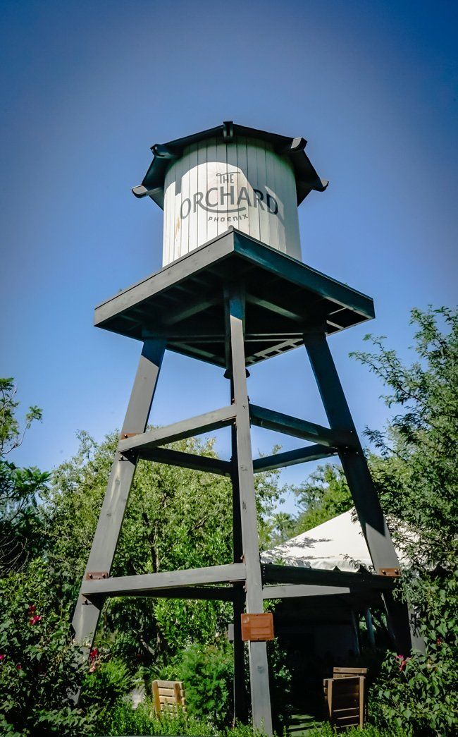 A water tower with the word orchard on it is surrounded by trees.