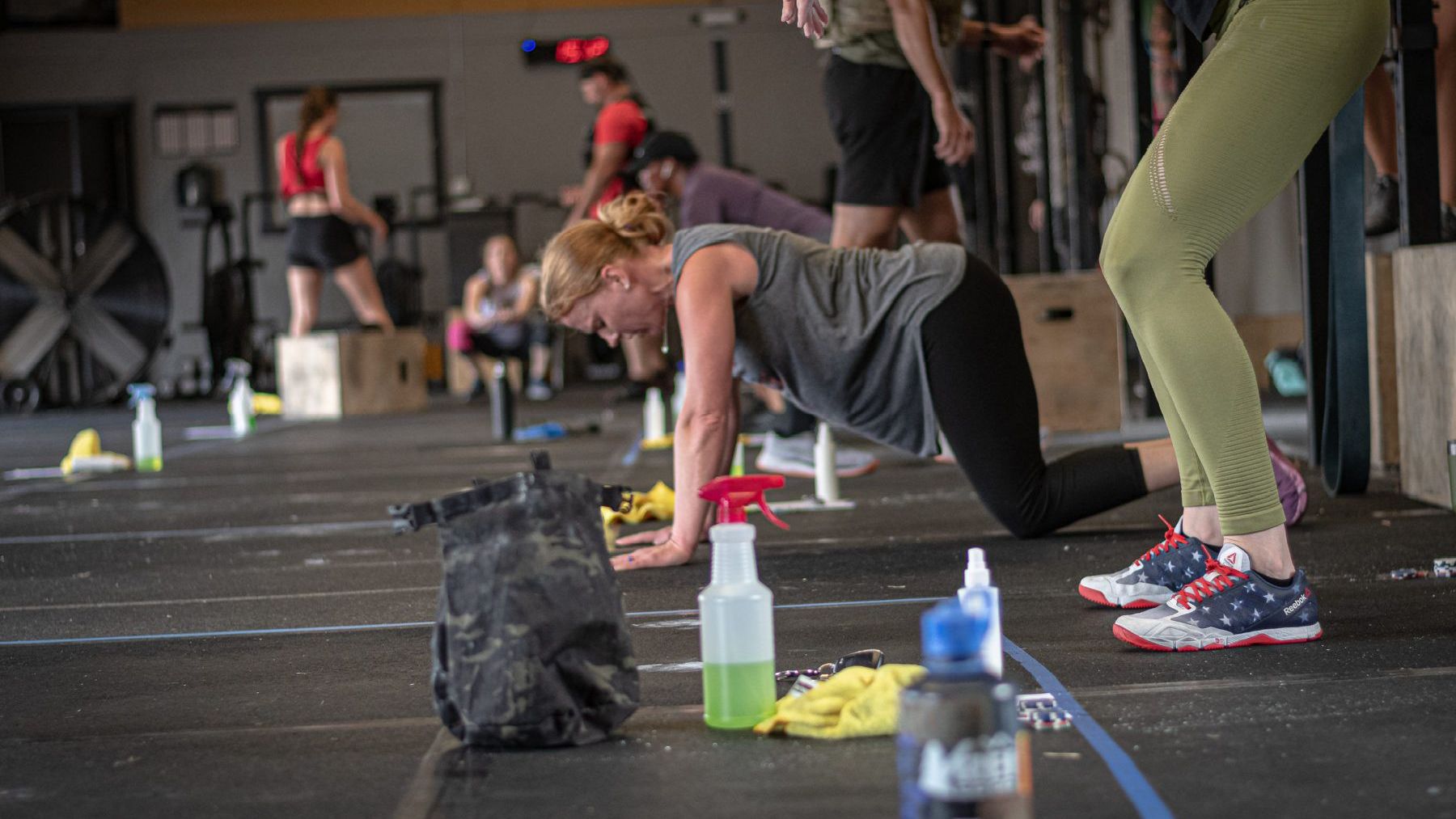 A woman is doing push ups on the floor in a gym.