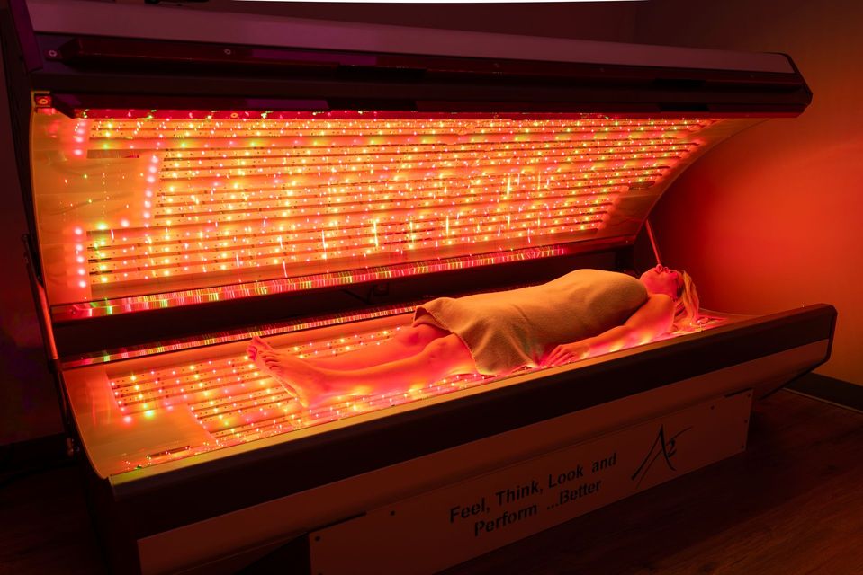 A woman is laying in a bed with red lights on it.